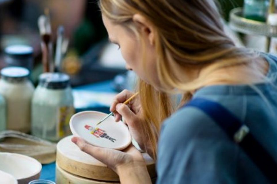 Young female artist painting Xmas decoration on handmade ceramics