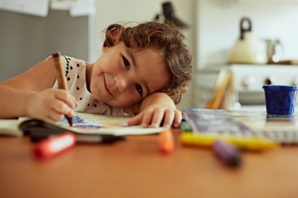 Portrait of little girl coloring book in the kitchen