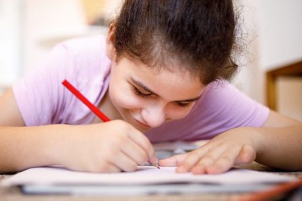 Girl lying on the floor while drawing on paper